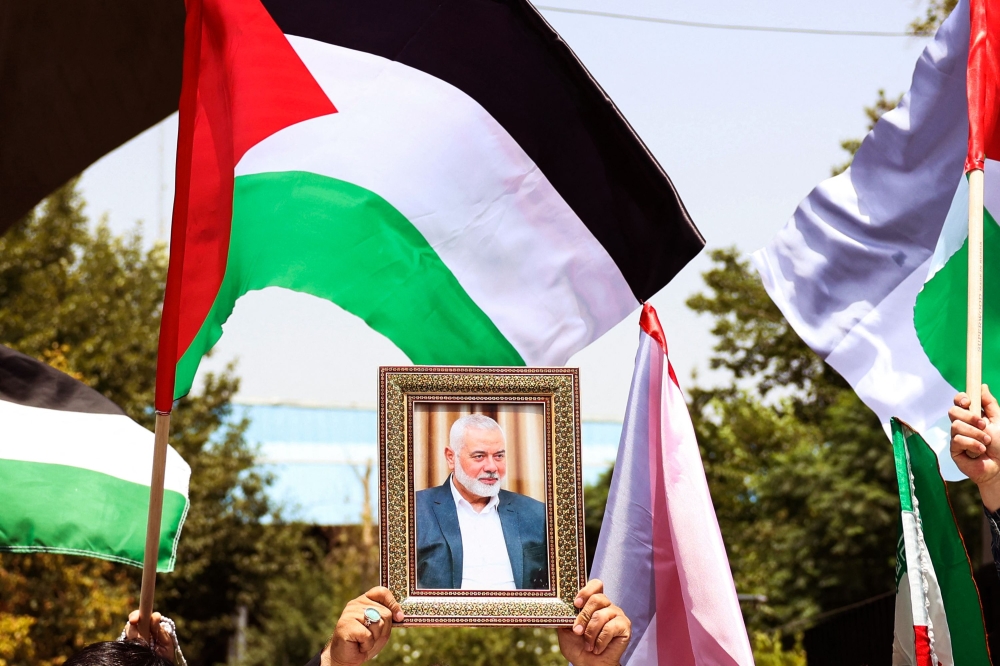 People hold up the Palestinian flag and a portrait of assassinated Hamas chief Ismail Haniyeh during a rally at Tehran University, in the Iranian capital Tehran on July 31, 2024. (Photo by AFP)