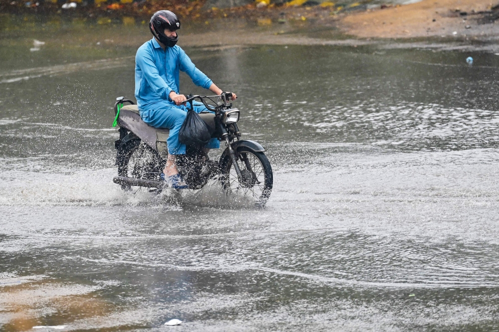 A man ride along a street during rainfall in Karachi on August 1, 2024. (Photo by Asif HASSAN / AFP)
 