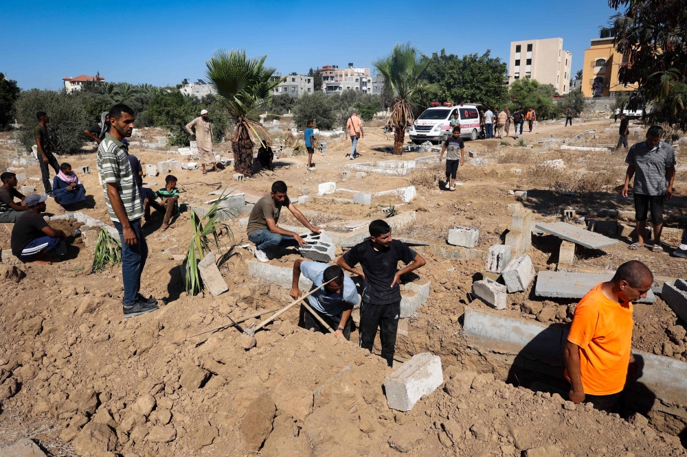 Palestinians dig graves at the al-Zawaida Cemetery, after the Israeli bombardment of the al-Bureij refugee Camp, in the central Gaza Strip on July 31, 2024. (Photo by Eyad Baba / AFP)