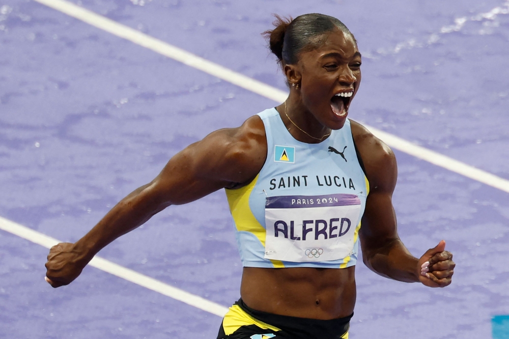 St Lucia's Julien Alfred celebrates after winning the women's 100m final of the athletics event at the Paris 2024 Olympic Games at Stade de France in Saint-Denis, north of Paris, on August 3, 2024. (Photo by Odd ANDERSEN / AFP)
