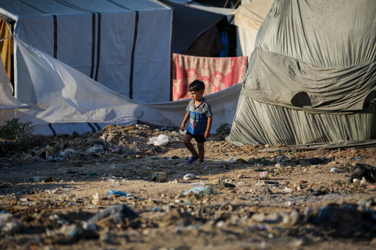 A child walks on street strewn with rubbish at the al-Maghazi Palestinian refugee camp, in the central Gaza Strip on August 2, 2024. Photo by Eyad BABA / AFP.