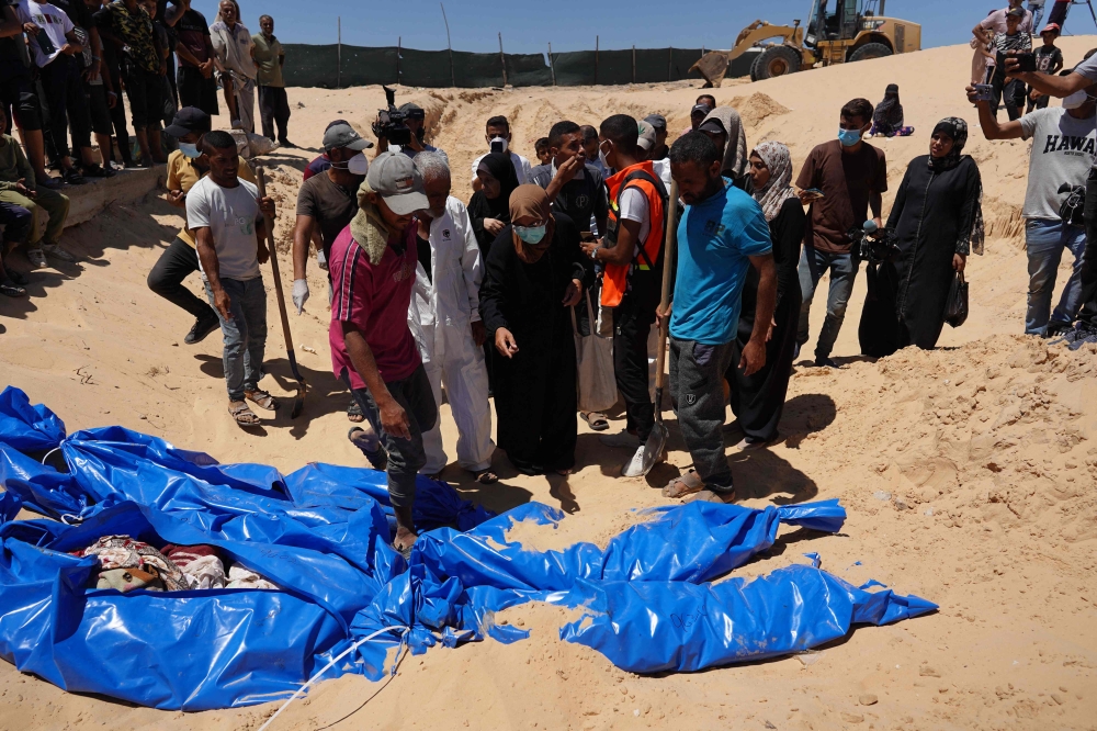 People burry bodies that were taken and later released by Israel during a mass funeral at a cemetery in Khan Yunis in the southern Gaza Strip on August 5, 2024. (Photo by Bashar Taleb / AFP)
