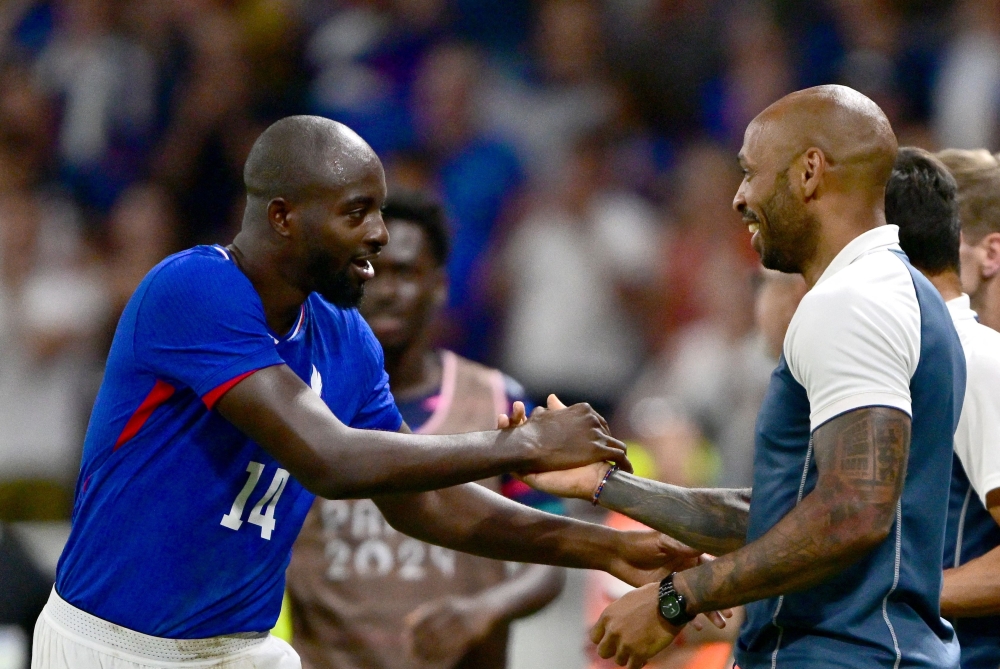 France's forward #14 Jean-Philippe Mateta celebrates scoring his team's second goal with France's coach Thierry Henry during the men's semi-final football match between France and Egypt during the Paris 2024 Olympic Games at the Lyon Stadium in Lyon on August 5, 2024. (Photo by Olivier CHASSIGNOLE / AFP)
