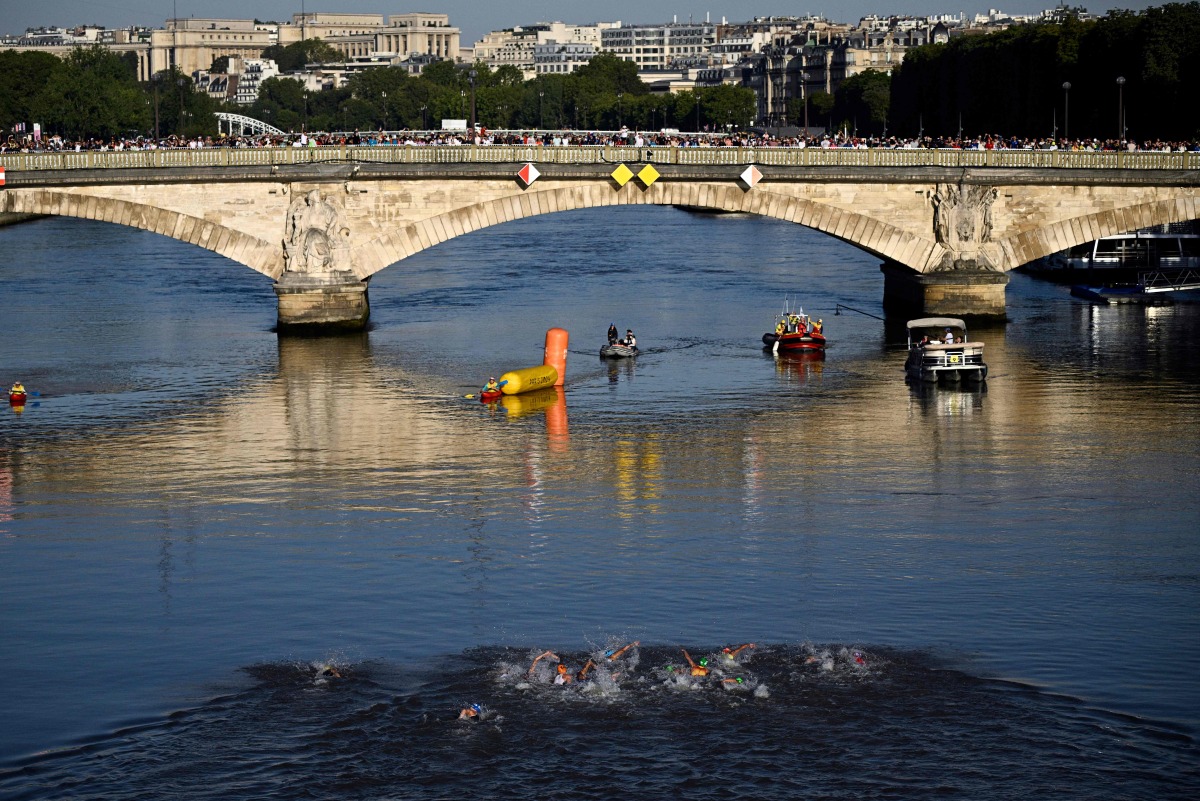 TOPSHOT - Athletes compete in the swimming race in the seine, during the mixed's relay triathlon, at the Paris 2024 Olympic Games, in central Paris, on August 5, 2024. (Photo by JULIEN DE ROSA / AFP)