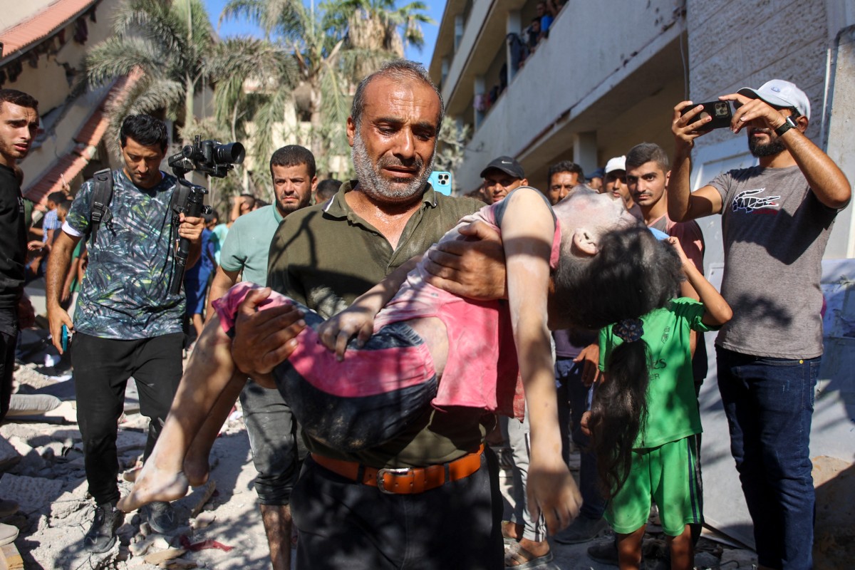 A man carries the body of a girl killed during Israeli bombardment on the Al-Nassr school that houses displaced Palestinians, West of Gaza city, on August 4, 2024. Photo by Omar AL-QATTAA / AFP.