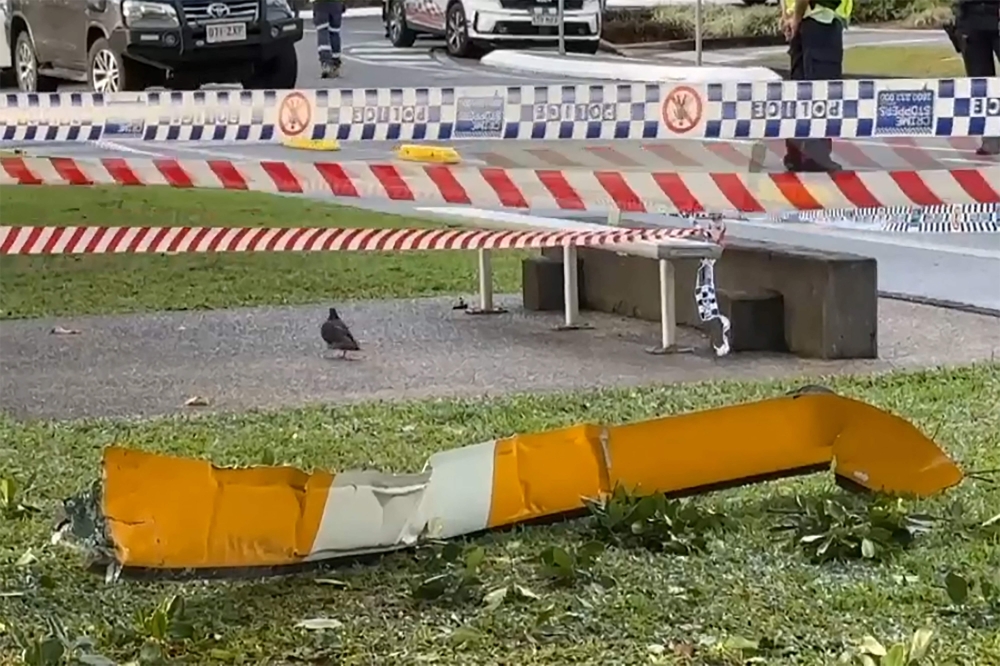 This frame grab taken from video footage provided by Australian Broadcasting Corporation (ABC) on August 12, 2024, via AFPTV shows a piece of the helicopter lying on a roadside after a helicopter crashed into the roof of a Hilton hotel in Cairns on August 12, 2024, killing the pilot and igniting a blaze on the building's roof. (Photo by Australian Broadcasting Corporation (ABC) / AFP) 