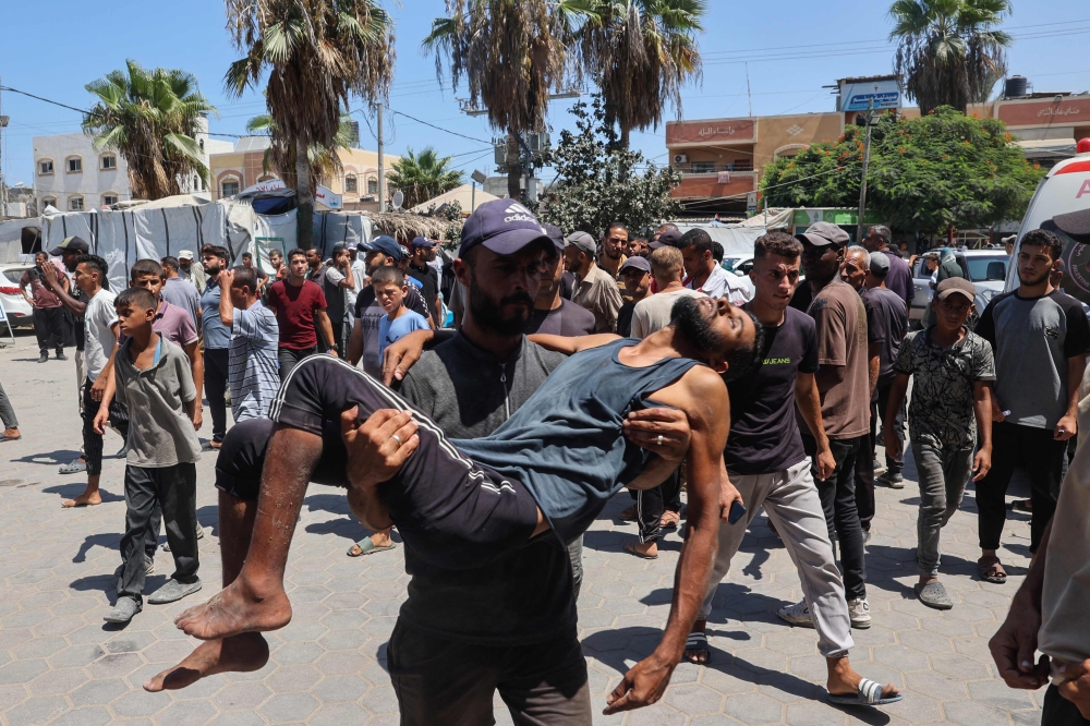 Palestinians transport people injured in Israeli bombardment to the Al-Aqsa Martyrs hospital in Deir el-Balah in the central Gaza Strip on August 13, 2024 amid the ongoing conflict between Israel and the Palestinian Hamas movement. (Photo by Eyad BABA / AFP)
