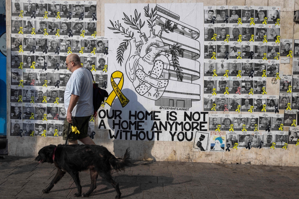 People walk past posters of Israelis held hostage by Palestinian militants in Gaza since October 7, on a street in Tel Aviv on August 13, 2024. (Photo by Oren Ziv / AFP)