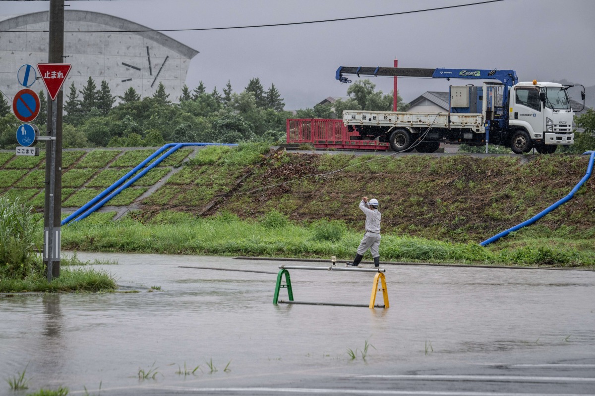 A worker walks in a flooded road in the wake of 