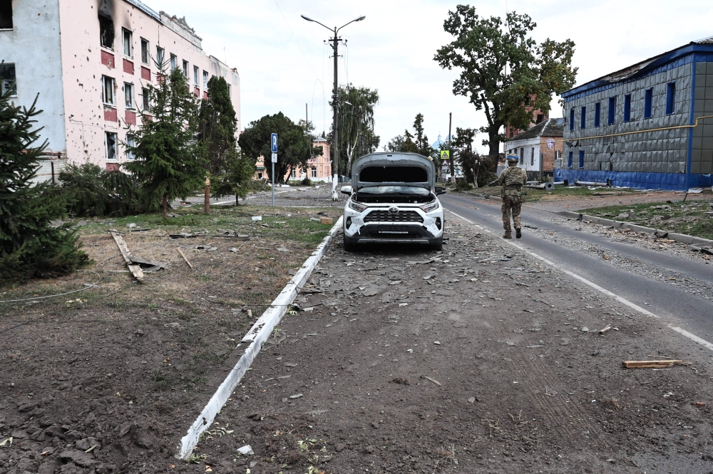 This photograph taken on 16 August, 2024, a media tour organised by Ukraine, shows a Ukrainian soldier walking on a damaged street in Ukrainian-controlled Russian town of Sudzha, Kursk region, amid the Russian invasion in Ukraine. (Photo by Yan DOBRONOSOV / AFP)
