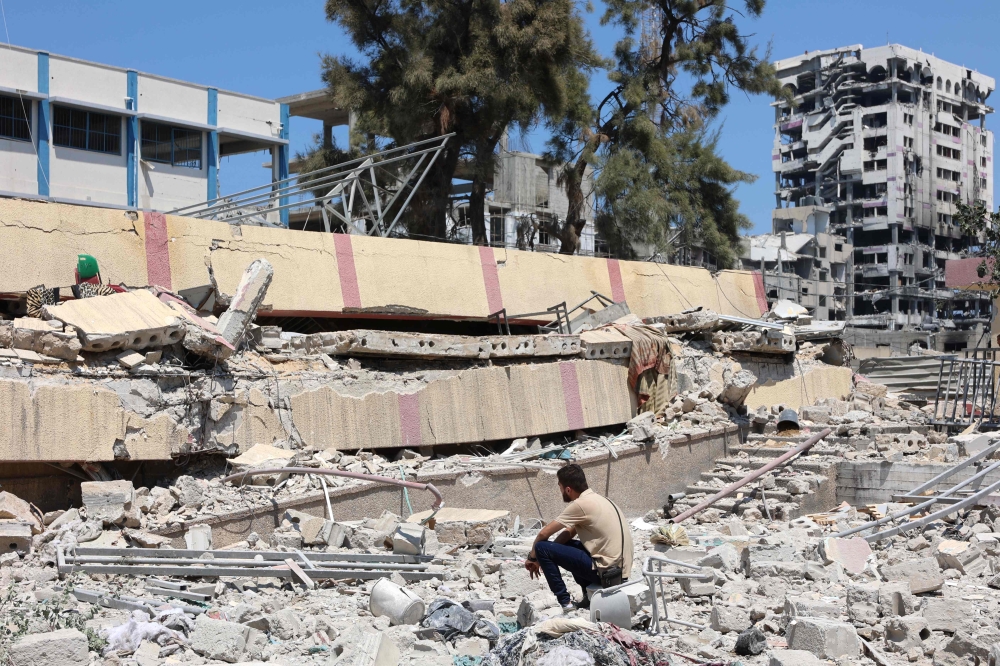 A man looks at the debris after an Israeli strike on a school, housing displaced Palestinians, in the Rimal neighbourhood of central Gaza City on August 20, 2024. (Photo by Omar AL-QATTAA / AFP)
