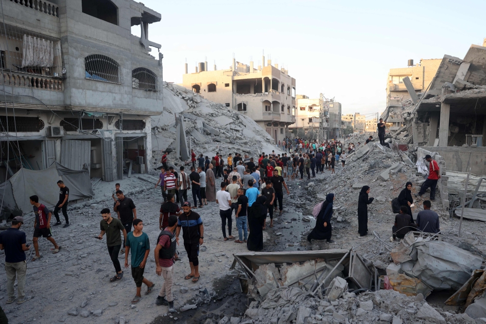 Palestinians gather to check a building shortly after it was levelled by Israeli bombing in the Nuseirat refugee camp in the central Gaza Strip on August 22, 2024. (Photo by Eyad BABA / AFP)
