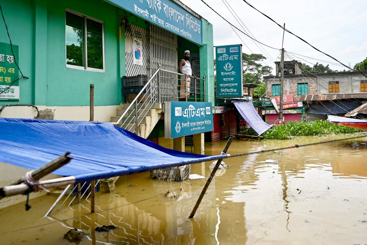 A man looks out from the porch of a bank partially submerged in floodwaters at Feni on August 24, 2024. (Photo by Munir UZ ZAMAN / AFP)