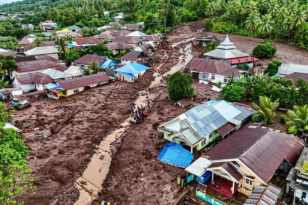 This aerial view shows rescue teams and residents searching for victims buried in mud after a flashflood hit the village of Rua located at the foot of Mount Gamalama, in Ternate, North Maluku on August 25, 2024. (Photo by AZZAM RISQULLAH / AFP)