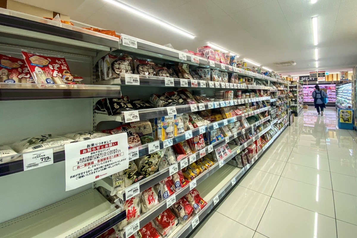 Empty shelves of rice are pictured in a supermarket with a notice written: 