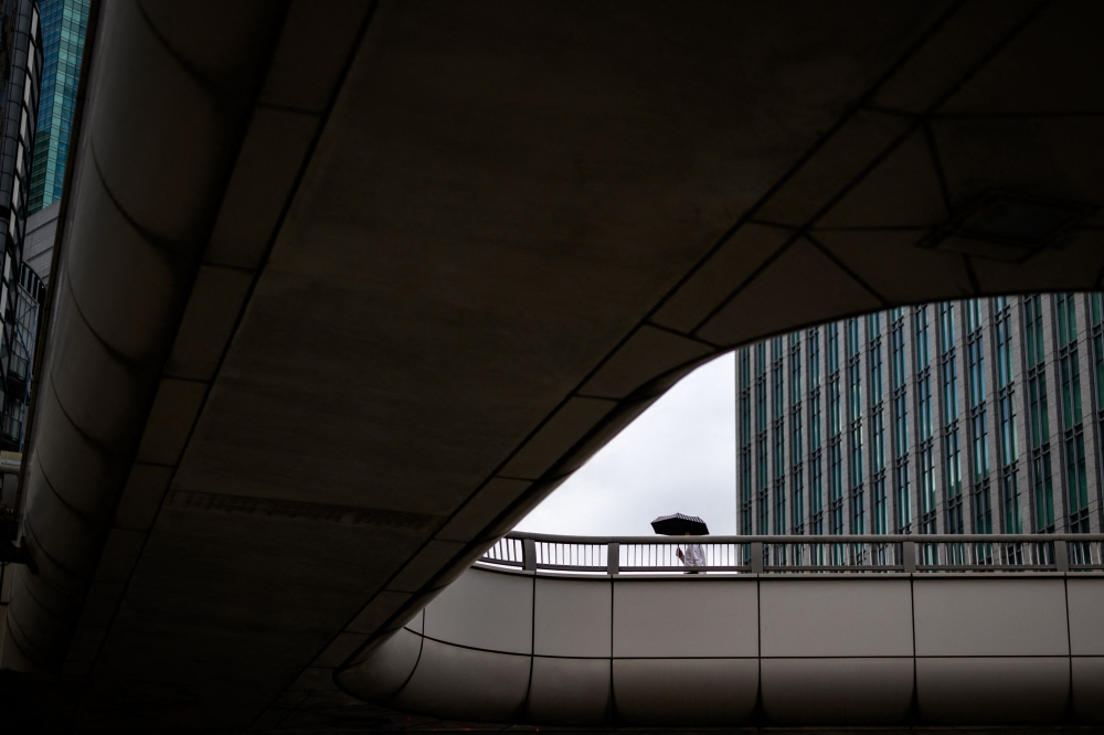 A man walks with an umbrella on a pedestrian overpass in the Ginza district of Tokyo on August 27, 2024. (Photo by Philip FONG / AFP)
 