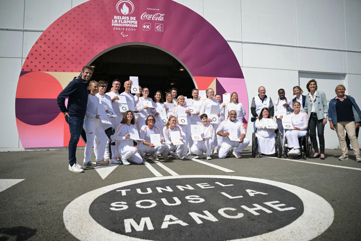 French President of the Paris 2024 Olympics and Paralympics Organising Committee (COJO) Tony Estanguet (L) poses with torchbearers of the Paris 2024 Paralympic Games during a ceremony for the arrival of the Paralympics flame at the entrance of the Channel Tunnel in Coquelles, northern France, on August 25, 2024. Photo by Lou Benoist / AFP.