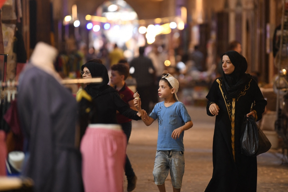 People walk along an alley during the reopening of restored historic bazaars that were damaged during the Syrian conflict in the northern city of Aleppo on August 28, 2024. (Photo by AFP)