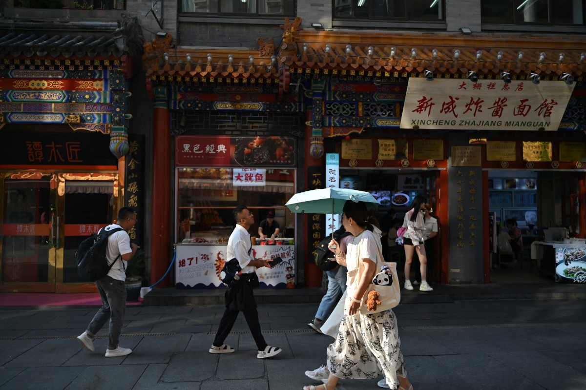 People walk along the Dazhalan street in Beijing on August 29, 2024. (Photo by ADEK BERRY / AFP)
