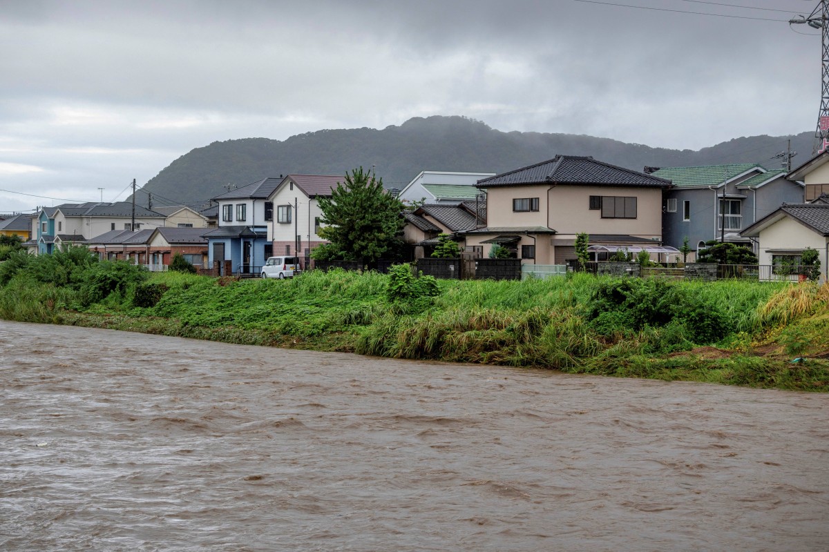 Muddy waters of the Kaneme River flow past houses lined up behind the river's bank in the aftermath of Typhoon Shanshan in Hiratsuka City, Kanagawa prefecture on August 30, 2024. Photo by Kazuhiro NOGI / AFP.