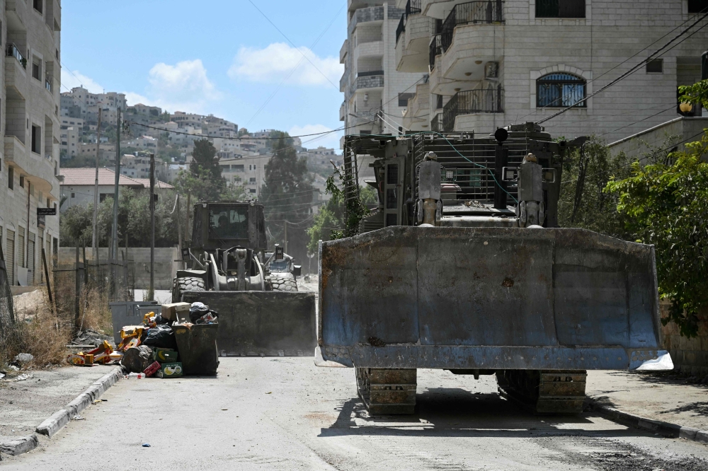 Israeli bulldozers drive in a street during an army raid in Jenin in the occupied-West Bank on August 31, 2024. (Photo by RONALDO SCHEMIDT / AFP)
