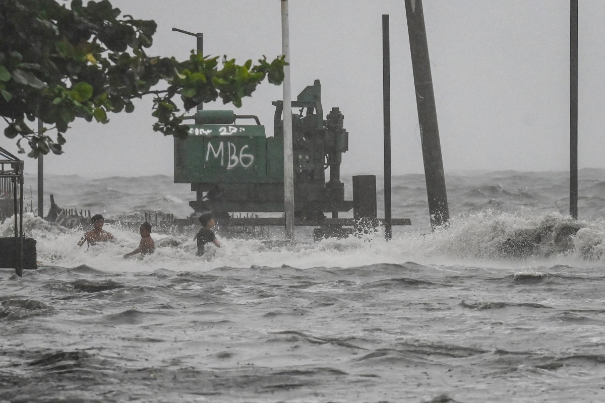 Youths wade in a storm surge along Manila Bay amid heavy rains brought by Tropical Storm Yagi in Manila on September 2, 2024. Photo by JAM STA ROSA / AFP