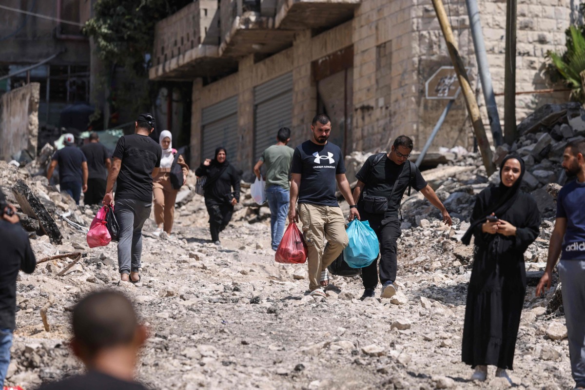 Palestinians walk on a street torn up by bulldozers after an Israeli raid in the eastern neighbourhood of Jenin city in the occupied West Bank, yesterday. (AFP)