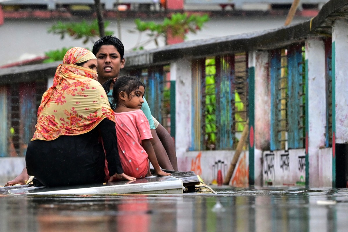 A family uses a makeshift raft to make their way through the flood waters in Daganbhuiyan in Feni, on August 25, 2024. (Photo by Munir Uz Zaman / AFP)
