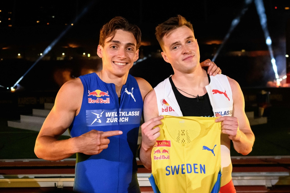 Swedish pole vaulter Armand Duplantis (L) presents a Sweden jersey to be worn by Norwegian hurdler and sprinter Karsten Warholm after winning a head-to-head exhibition 100m sprint race on the sideline of the IAAF Diamond League 