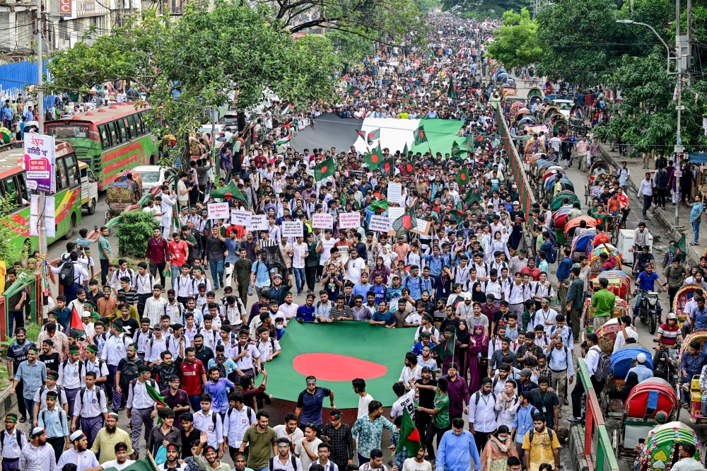 Demonstrators carry Bangladesh's national flag (front) during 'Martyr March', a rally organised by Students Against Discrimination to mark one month to the ousting of the country's former Prime Minister Sheikh Hasina, in Dhaka on September 5, 2024.  (Photo by Munir Uz Zaman / AFP)