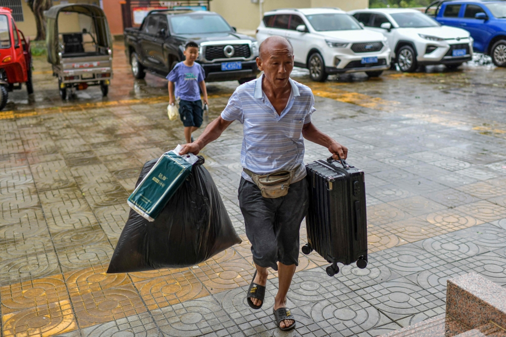 A local resident carries food and his luggage to a temporary shelter in a primary school ahead of the expected landfall of Super Typhoon Yagi in Wenchang, in southern China's Hainan province on September 6, 2024. (Photo by CNS / AFP) / China OUT