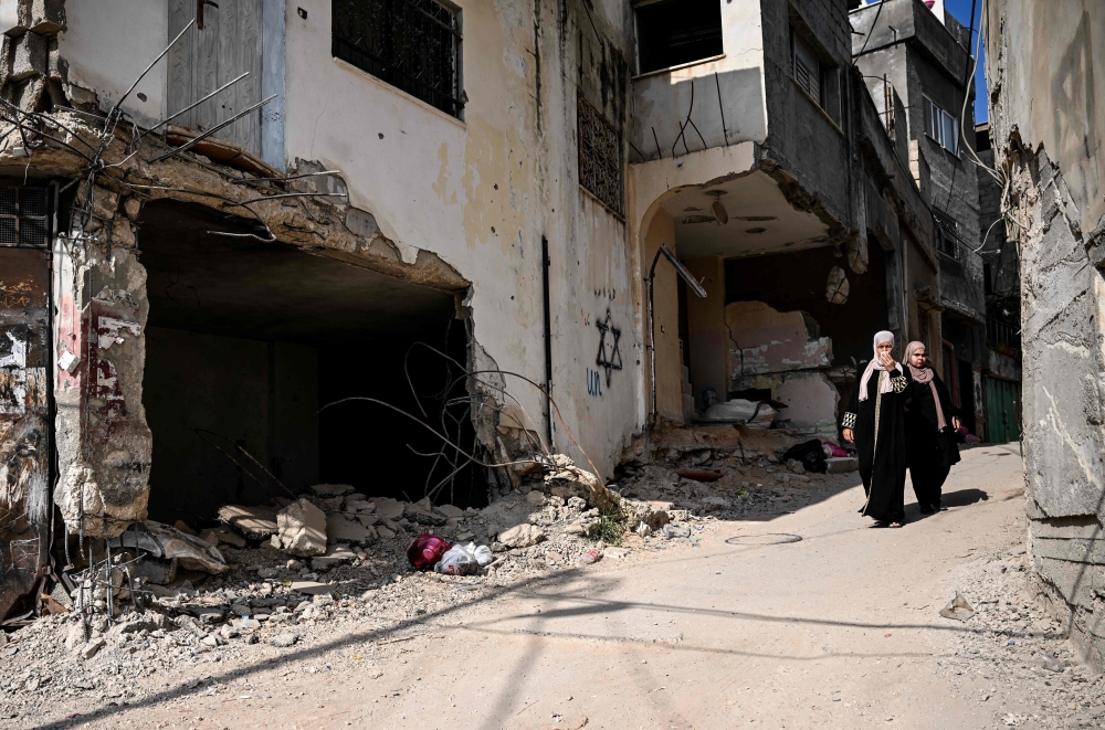 Residents walk amid the destruction following an Israeli military raid in the Jenin refugee camp, in the occupied West Bank on September 6, 2024. (Photo by Ronaldo Schemidt / AFP)