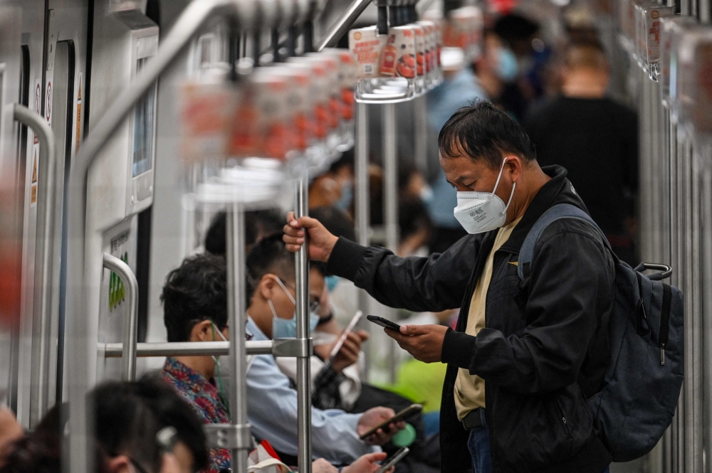 People commute on a train in Shanghai on September 20, 2022. Photo by Hector RETAMAL / AFP