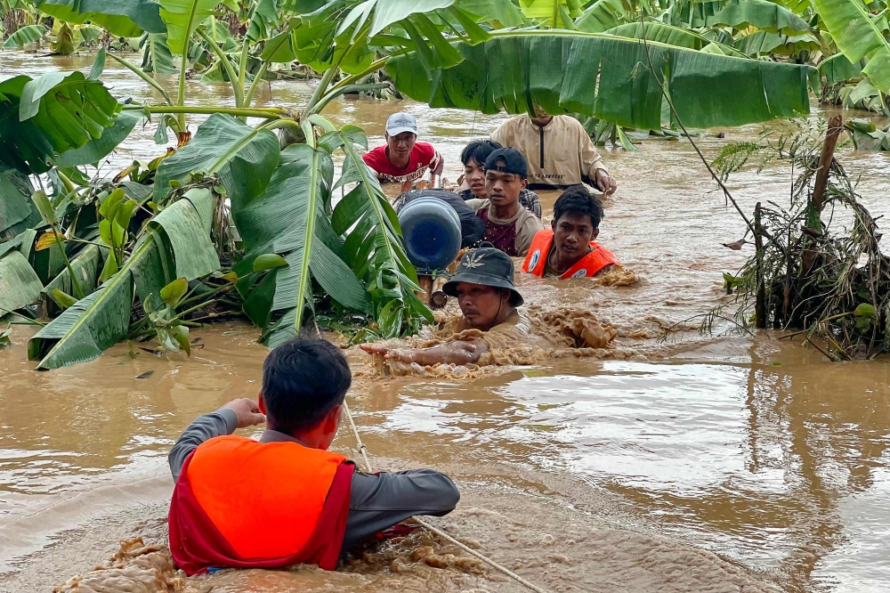 Residents are helped through high flood waters by police in Pyinmana town in Myanmar's Naypyidaw region on September 13, 2024, following heavy rains in the aftermath of Typhoon Yagi. (Photo by Sai Aung Main / AFP)