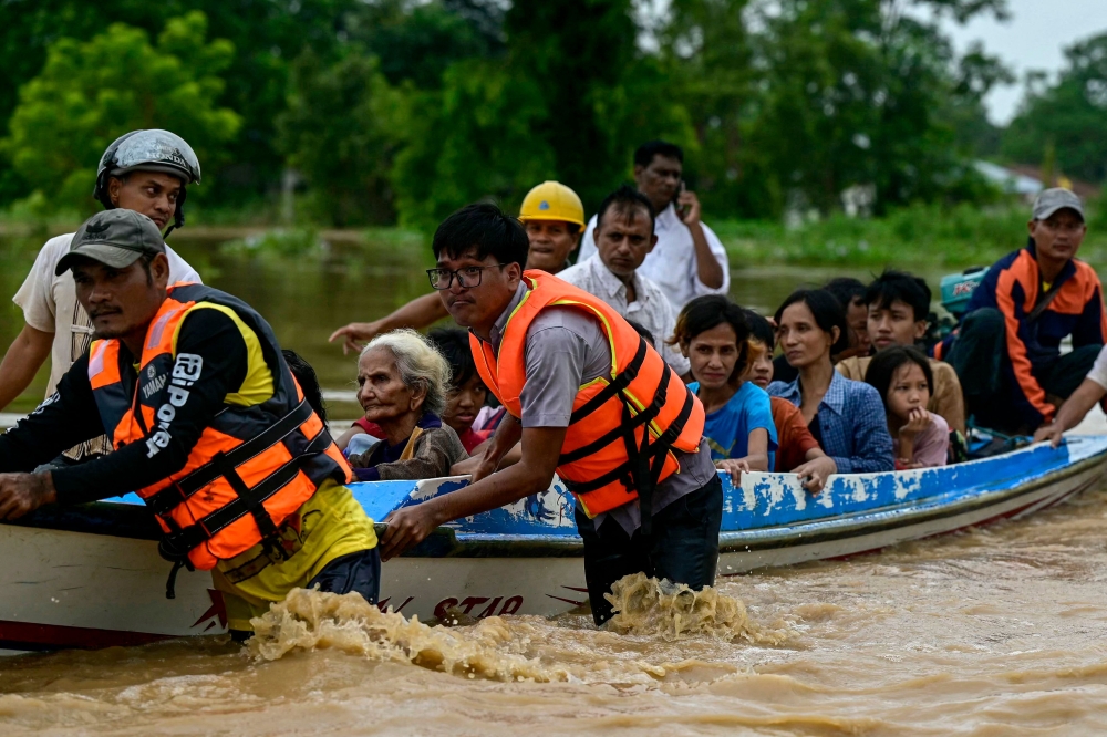 Flood-affected residents are transported on a rescue boat in Taungoo, Myanmar's Bago region on September 14, 2024. (Photo by Sai Aung MAIN / AFP)