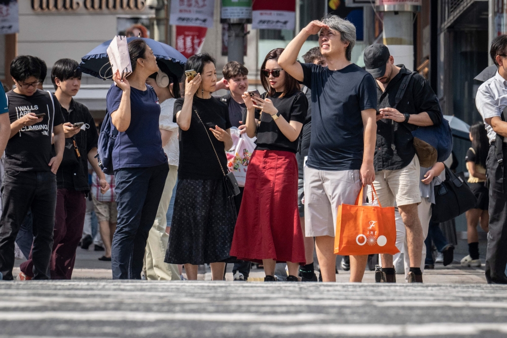 File picture: People wait to cross a street during hot weather in Tokyo on September 19, 2024. (Photo by Yuichi Yamazaki / AFP)