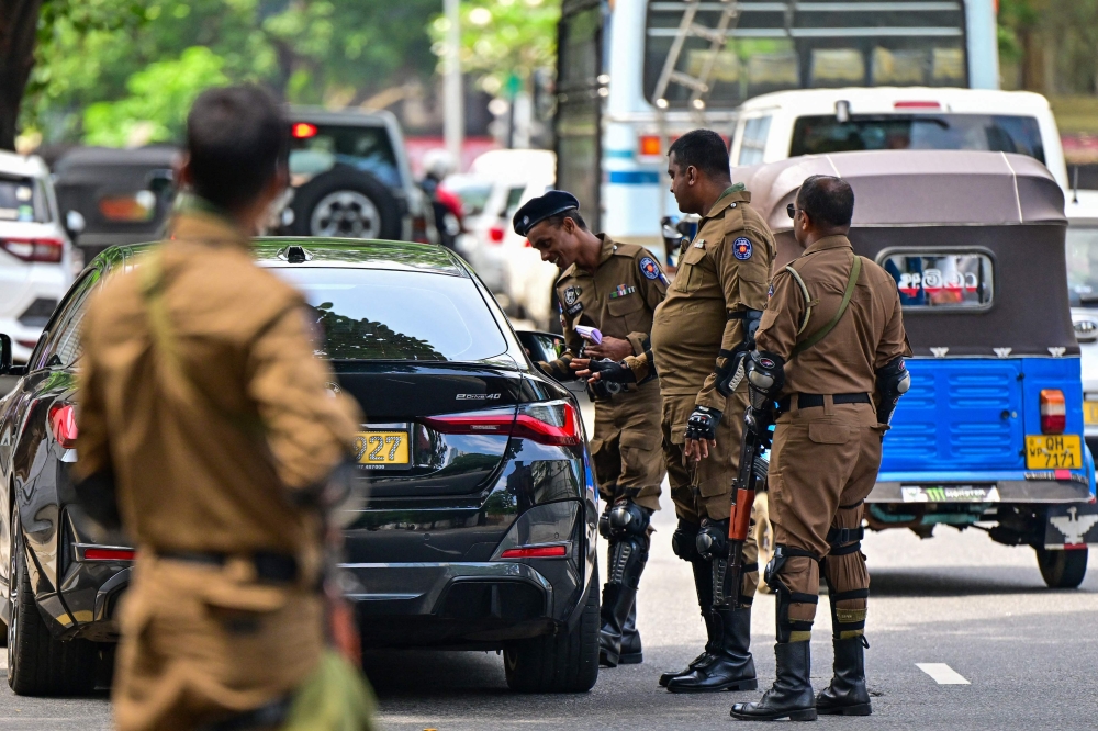 Sri Lankan police combat officers inspect a car at a road checkpoint ahead of the upcoming presidential elections, in Colombo on September 19, 2024. (Photo by Ishara S. Kodikara / AFP)