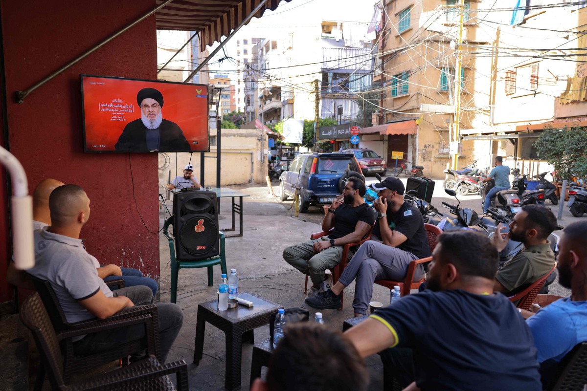 People watch on a television screen Hezbollah leader Hassan Nasrallah as he addresses the nation via video link, at a cafe in the Shiyah neighbourhood of Beirut's southern suburbs on September 19, 2024. (Photo by ANWAR AMRO / AFP)