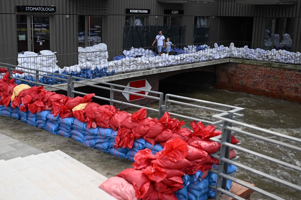 :People walk past sandbags piled up to protect a building against the floods in Wroclaw, Poland, on September 19, 2024. (Photo by Sergei Gapon / AFP)
