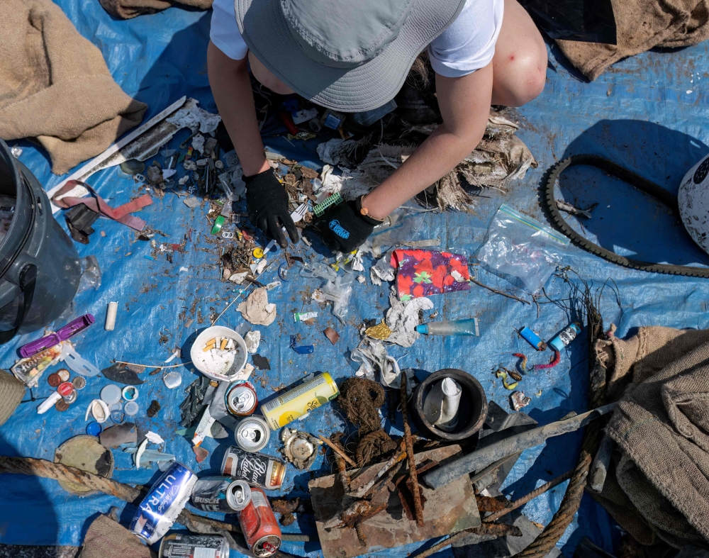 Laurence Martel, Plastic Pollution Coordinator of the Blue Organization sorts through trash collected on the shore and in the water of the Saguenay Fjord during the Blue Expedition, in Petit-Saguenay, Quebec, Canada, July 24, 2024. (Photo by Sebastien ST-JEAN / AFP)