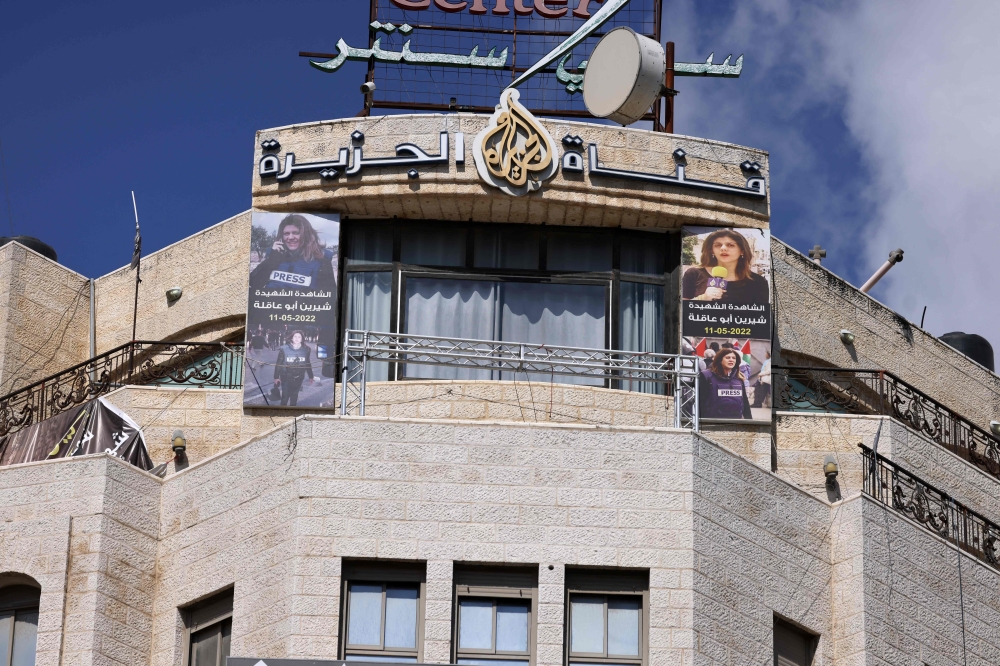 Pictures of slain al-Jazeera journalist Shireen Abu Akleh hang on the facade of the building housing the television station's office in Ramallah in the occupied West Bank. (Photo by Jaafar Ashtiyeh / AFP)
 