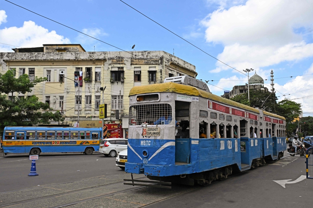 In this photo taken on September 8, 2024, passengers commute in a tram along a street in Kolkata. (Photo by Dibyangshu Sarkar / AFP) 