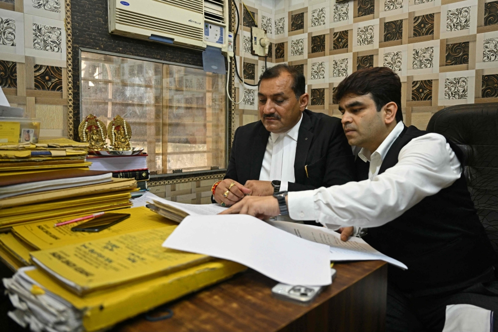 In this photograph taken on September 6, 2024, lawyers go through a case file inside their chamber at the court complex in Ghaziabad. (Photo by Money Sharma / AFP) 