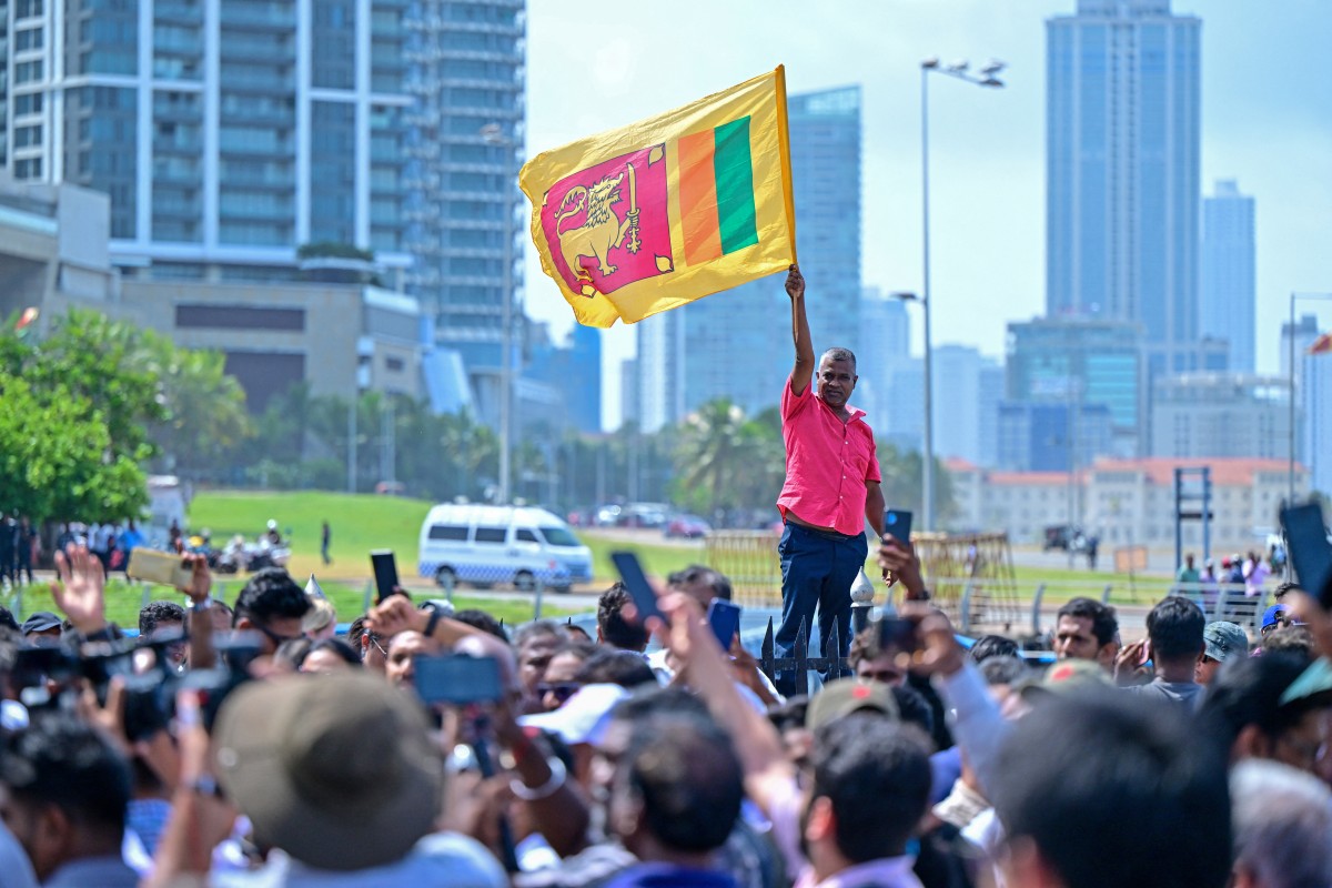 A supporter of Sri Lanka's newly elected President Anura Kumara Dissanayaka, waves country's national flag near the Presidential Secretariat after Dissanayaka's swearing-in ceremony in Colombo on September 23, 2024. Photo by Ishara S. Kodikara / AFP.