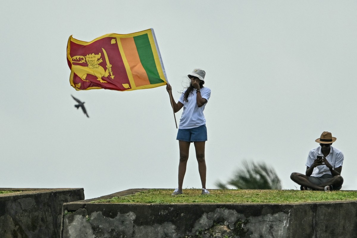 Photo used for a demonstration purpose. A woman with a Sri Lankan national flag stands at the Galle fort while watching the play of the fourth day of first Test cricket match between Sri Lanka and New Zealand at the Galle International Cricket Stadium in Galle on September 22, 2024. Photo by IDREES MOHAMMED / AFP.