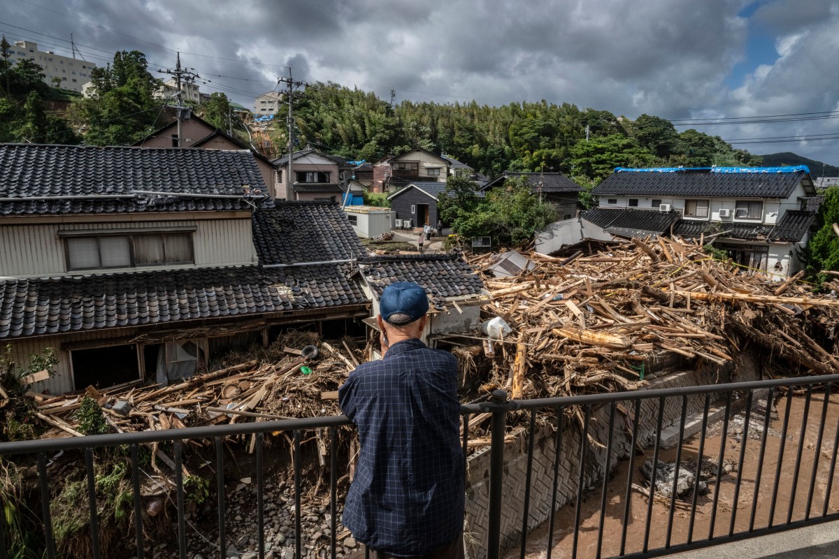 A man looks on as debris washed away from flooding is seen piled by houses along the Tsukada river following heavy rain in Wajima city, Ishikawa prefecture on September 23, 2024. Photo by Yuichi YAMAZAKI / AFP.