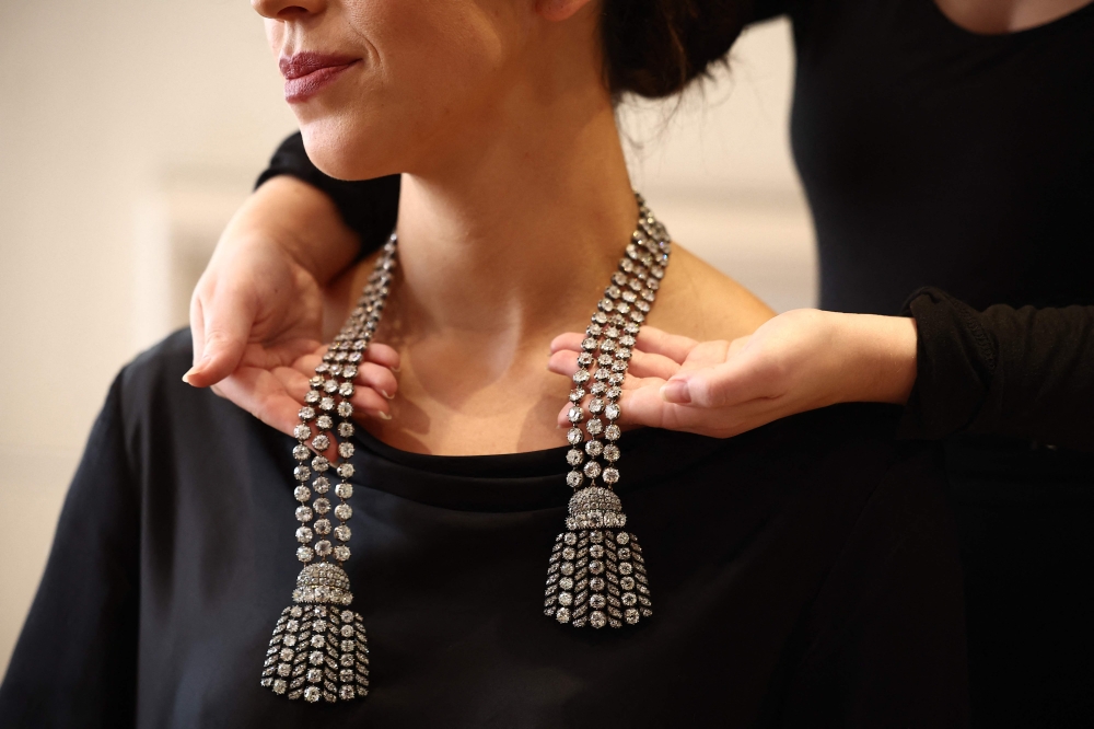 A gallery assistant poses wearing an 18th century diamond jewel necklace weighing approximately 300 carats at a press preview at Sotheby's in London on September 23, 2024. (Photo by Henry Nicholls / AFP)