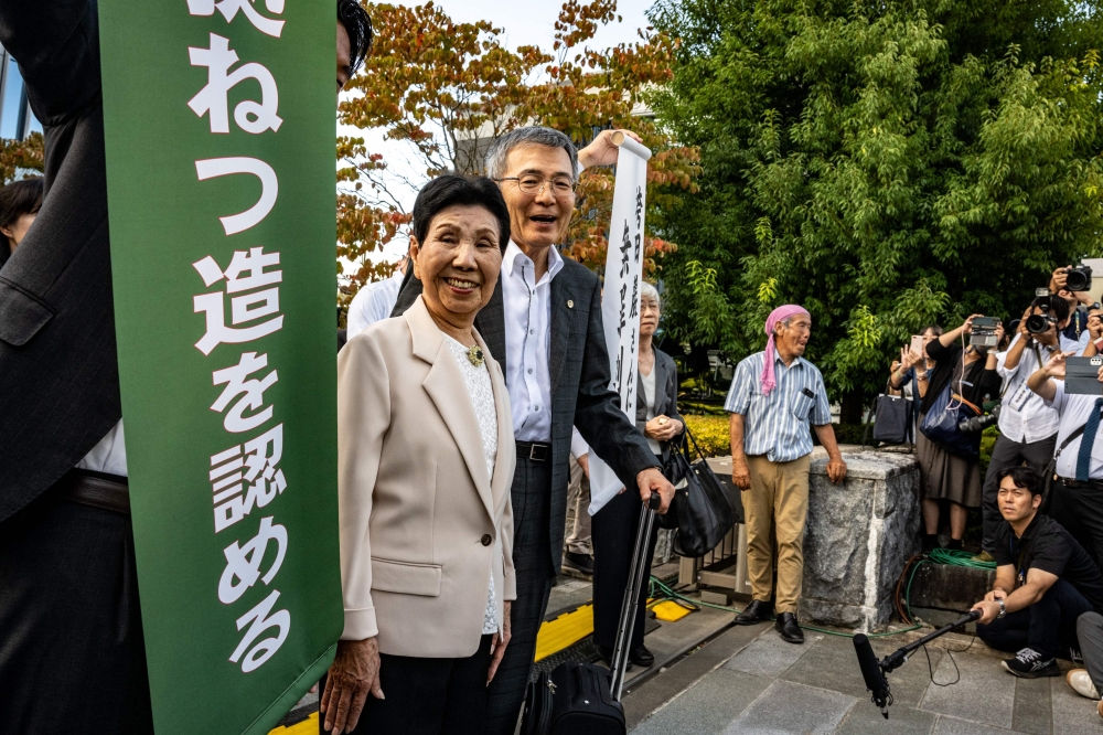 Hideko Hakamada (C), sister of Iwao Hakamada (not pictured), and lawyers pose with a white banner (R) reading 