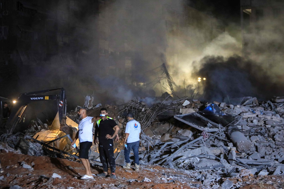 Rescuers stand on the rubble of a builiding destroyed in an Israeli air strike in the Haret Hreik neighbourhood of Beirut's southern suburbs on September 27, 2024. (Photo by AFP)
