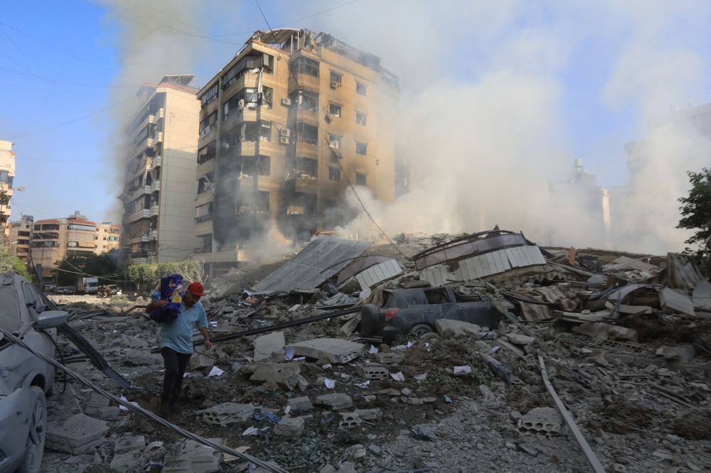 A man walks through the rubble as people check on September 28, 2024 the devastation in the Hadath neighbourhood of Beirut's southern suburbs in the aftermath of overnight Israeli airstrikes on the outskirts of the Lebanese capital. Photo by AFP